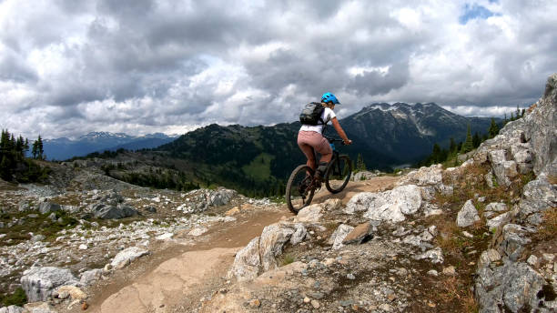 istock Female mountain biker rides up alpine trail 1281595415