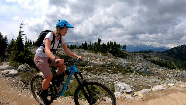 istock Female mountain biker rides up alpine trail 1281595427