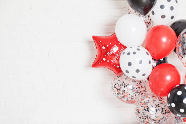 Beautiful white brick wall background with red, white and black balloons. Happy birthday. Concept of happiness and joy.  Copy Space stock photo