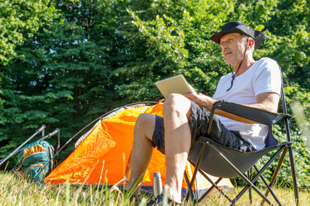 istock Senior man with digital tablet camping in nature 1281596678