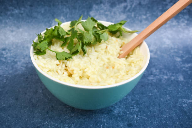 istock Rice in a bowl and a wooden spoon on a blue background 1281597160