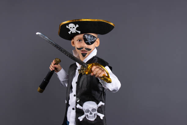 istock Classic pirate captain with painted face, sword and telescope. Isolated on a gray background with plenty of copy space. Happy Halloween 1281598220