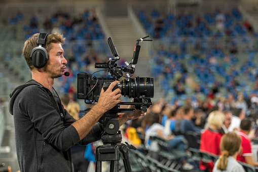 Side view of cameraman shooting basketball match in stadium.