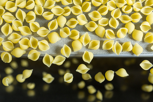The pasta falls down into the distribution compartment of the production line.