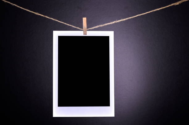 Blank polaroid photographs hanging Close-up of blank polaroid photographs hanging on a clothesline in darkroom. darkroom photos stock pictures, royalty-free photos & images