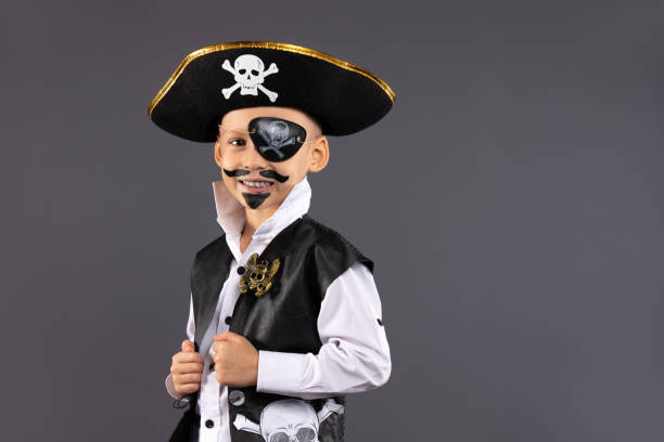 istock Little boy dressed as a pirate with makeup on his face is having fun at a Halloween party. Face painting for children. Isolated gray background with blank space. 1281606193