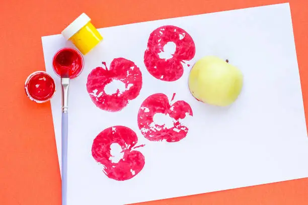 Photo of Children's crafts. Print of apples on colored paper.