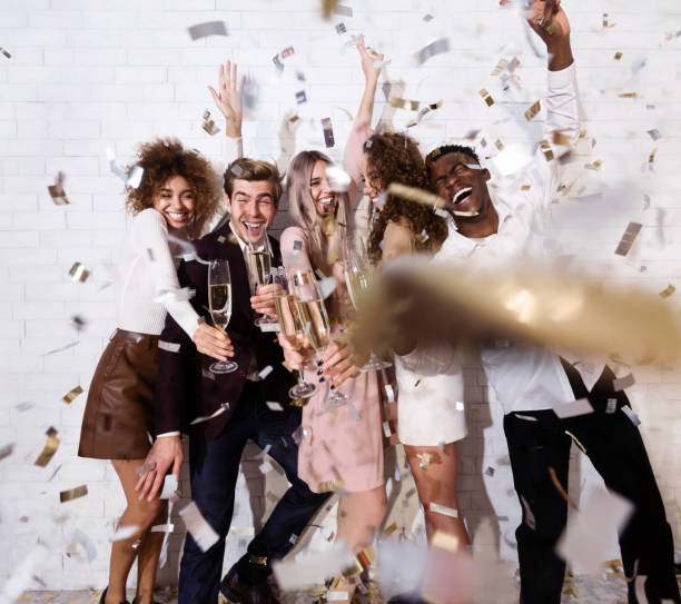 istock Happy young people celebrating drinking champagne showered with confetti indoor 1281607796