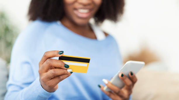 istock Black woman using phone and credit card at home 1281607941
