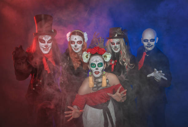 Group of people with creepy Halloween make up dead day calavera style having fun and party Group of people with creepy Halloween make up dead day calavera style having fun and party on red and blue smoke background face paint halloween adult men stock pictures, royalty-free photos & images