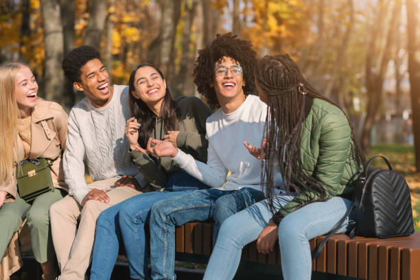 istock Teenagers having fun at public park, sitting on bench, talking 1281613649