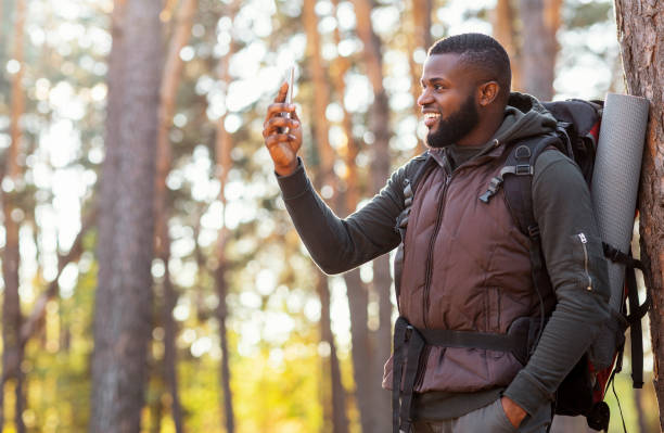 istock Happy black guy holding smartphone, finally got gps in woods 1281613732