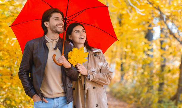 istock Happy lovers walking under red umbrella at rainy autumn day 1281614846