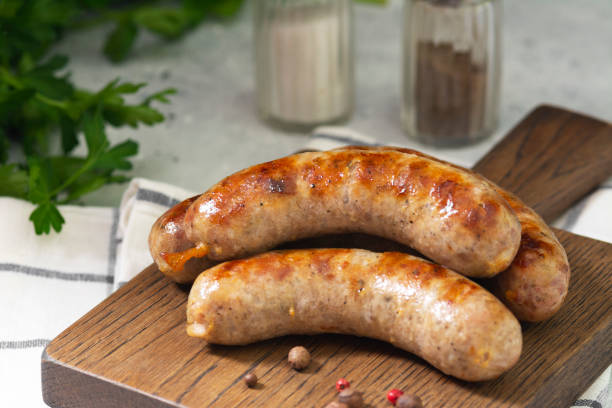 istock Grilled sausages on a wooden Board on a light gray kitchen table 1281615137