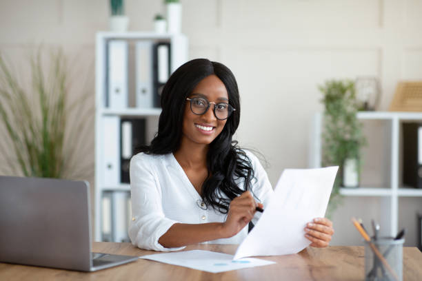 istock Beautuful black business lady working with documents at desk in office 1281616311