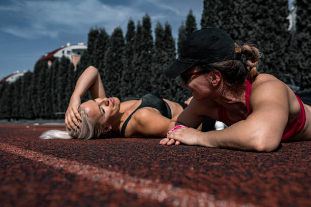Two female athletes resting and smiling at running track outdoors on a beautiful day