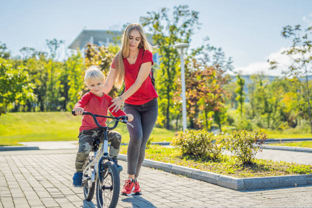 istock Young mother teaching her son how to ride a bicycle in the park 1281617900