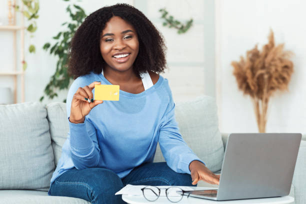 istock Black woman using laptop and showing credit card 1281621797