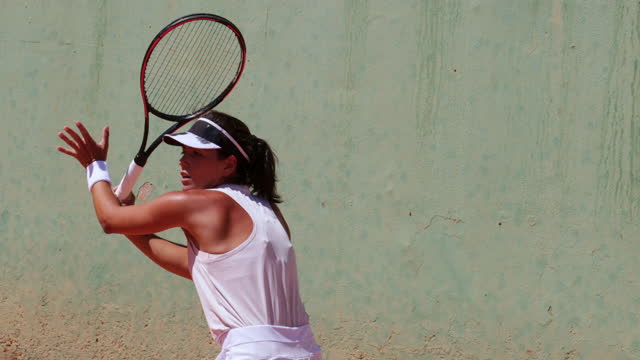 Female tennis player hitting ball on clay court