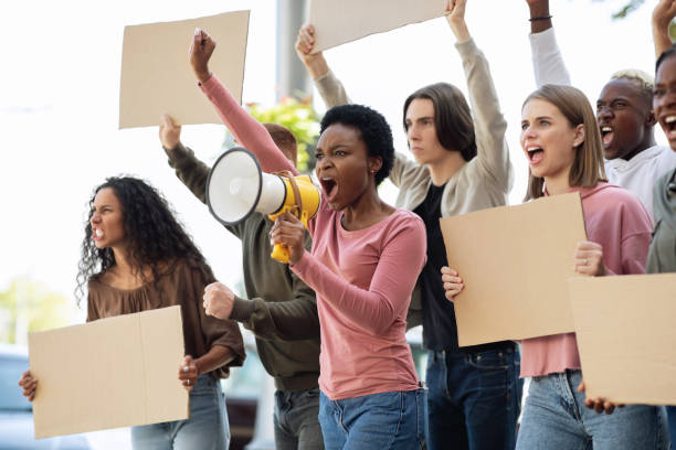 istock Multiethnic demonstrators protesting on the street, holding megaphone and placards 1281621911