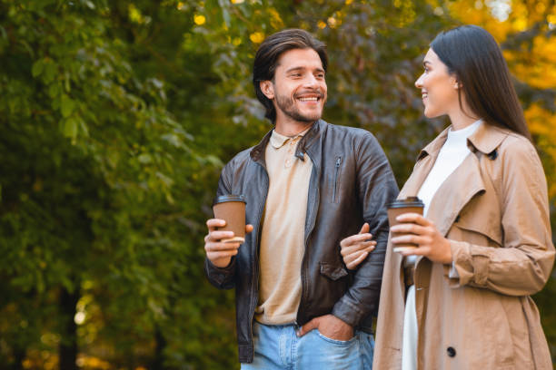 istock Cheerful man and woman drinking coffee while dating in forest 1281621962