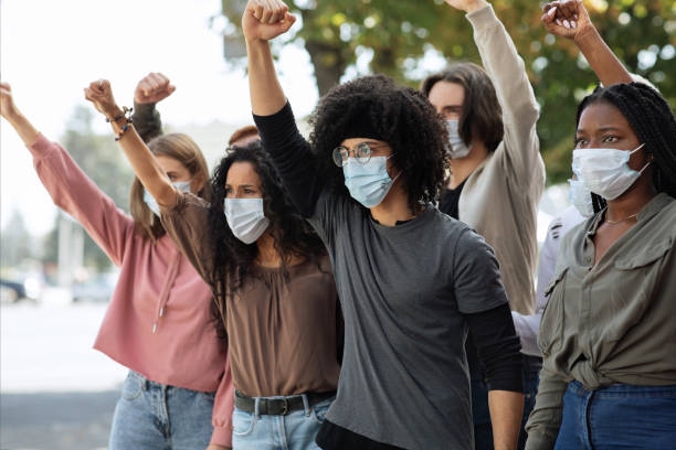 istock Students wearing protective face mask protesting and raising fists up 1281622215