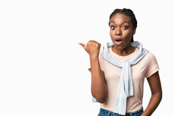 istock Shocked Black Millennial Woman Pointing Thumb Aside Over White Background 1281623860