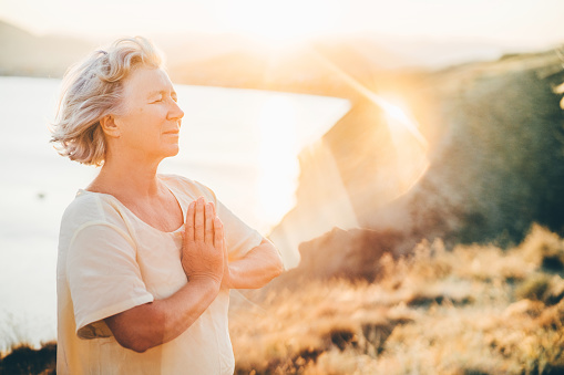 Woman practicing Yoga, meditation close to the sea. She doing different poses on beautiful landscape. Concept of finding yourself and Healthy Life.