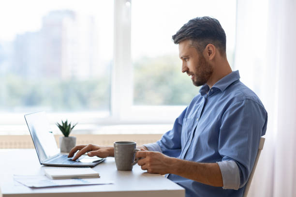 istock Remote Work. Male Freelancer Using Laptop And Drinking Coffee At Home Office 1281624465
