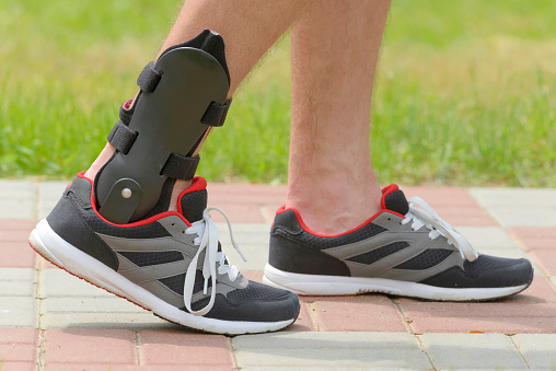 Man in athletic sneakers wearing ankle orthosis or brace
