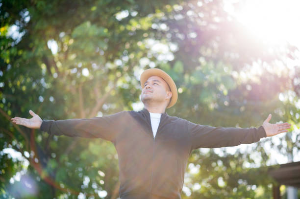 istock Asian freelancer put on brown hat working outdoor. Office worker or businessman stand alone and stretch the arm at garden area. Outdoor Activity Concept. 1281627231