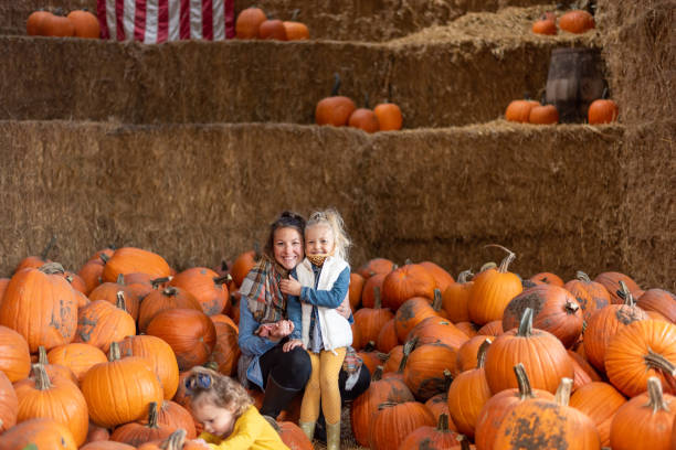 istock Smiling Mother And Daughter Standing Amidst Pumpkin 1281628915