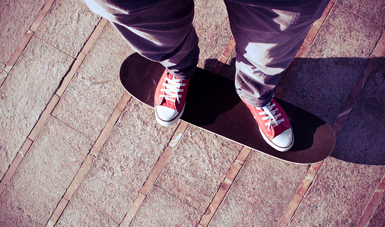 self-portrait of a young man wearing red sneakers on a skate board