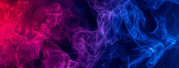 Photo of Conceptual image of colorful red and blue color smoke on dark black background.