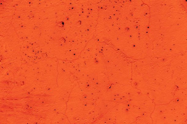 Orange concrete background texture with dark holes and cracks. The natural color of the old facade. Festive backdrop for design and decoration