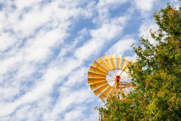 Yellow windmill photographed over a fluffy cloud sky