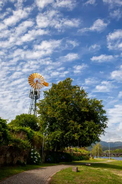 Yellow windmill photographed over a fluffy cloud sky in Ponte de Lima
