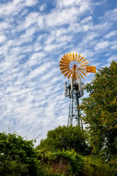 Yellow windmill photographed over a fluffy cloud sky