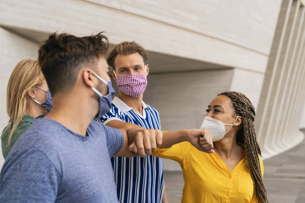 istock Young friends wearing face protective mask doing new social distancing greet with elbows bumps for preventing corona virus spread - Physical distance and friendship safety greetings concept 1281634797