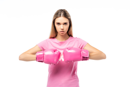 Woman in boxing gloves holding pink ribbon of breast cancer awareness isolated on white