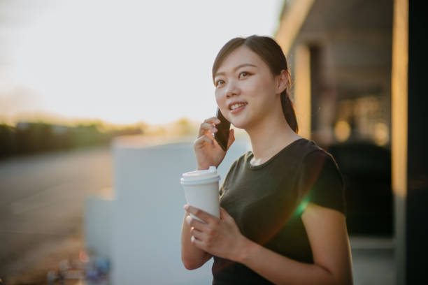 istock Young asian woman using smartphone and having take out coffee 1281640270