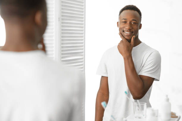 istock Well-Shaved Black Man Touching Smooth Face Standing In Modern Bathroom 1281642180