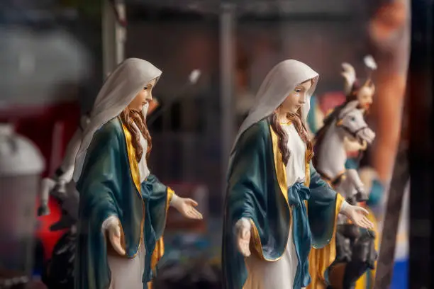 shop window displaying religious articles with small statues of the Virgin Mary In focus