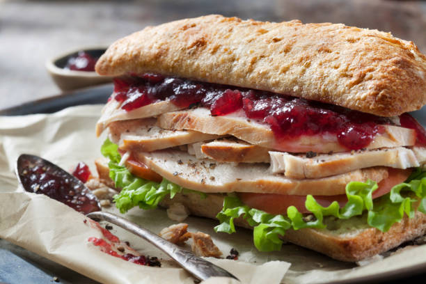 panino al tacchino arrosto con lattuga, pomodoro e salsa di mirtilli rossi su ciabatta bun - portion turkey sandwich close up foto e immagini stock