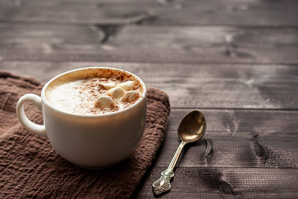 Cup of cappuccino with marshmallows and spoon White cup of cappuccino with marshmallows and spoon on a wooden table. Selective focus, copy space hot chocolate stock pictures, royalty-free photos & images