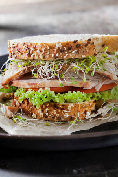 istock Roast Turkey Sandwich with Lettuce, Tomato and Pea Shoots on Whole Grain Bread 1281644908