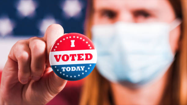 istock Woman showing elections sticker with face mask 1281645947