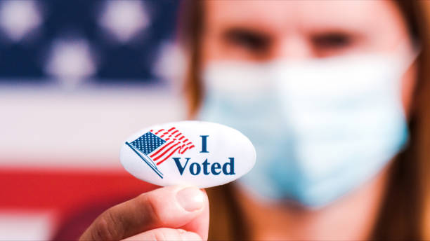 istock Woman showing elections sticker with face mask 1281645981