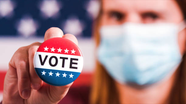 istock Woman showing elections sticker with face mask 1281645998