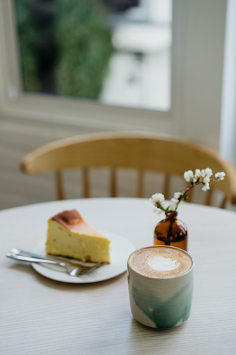 Coffee and a slice of cheesecake on top of table